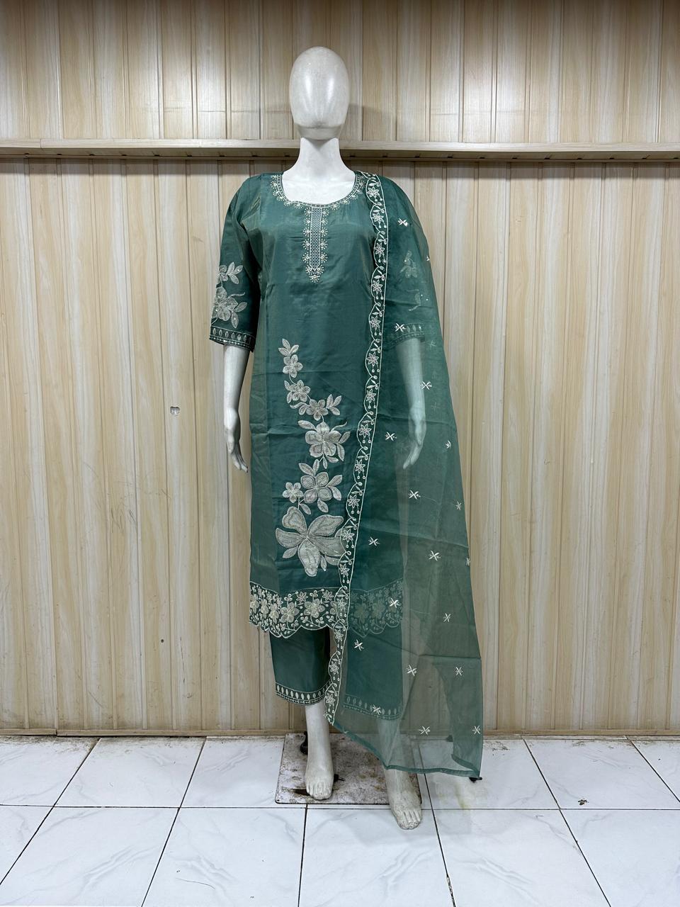 Green embroidered outfit on a mannequin against a striped