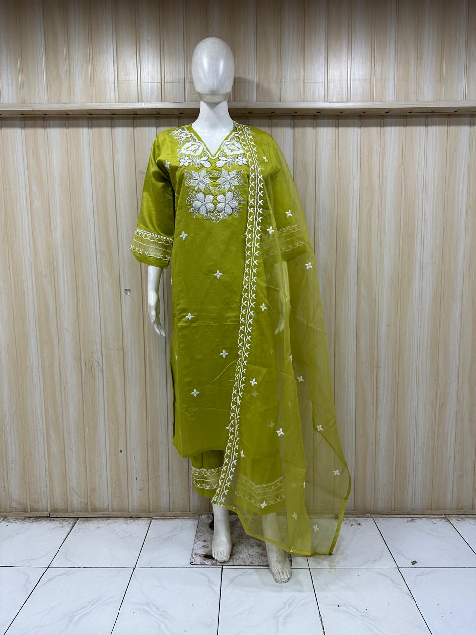 Green embroidered traditional outfit on a mannequin against a striped
