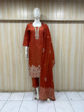 Mannequin wearing a rust-colored embroidered outfit against a striped
