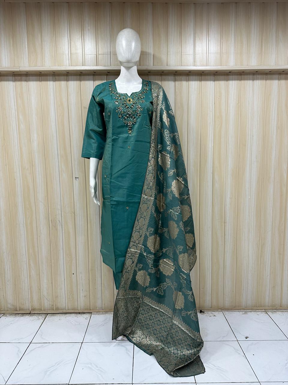 Green traditional outfit with a dupatta on a mannequin against a striped