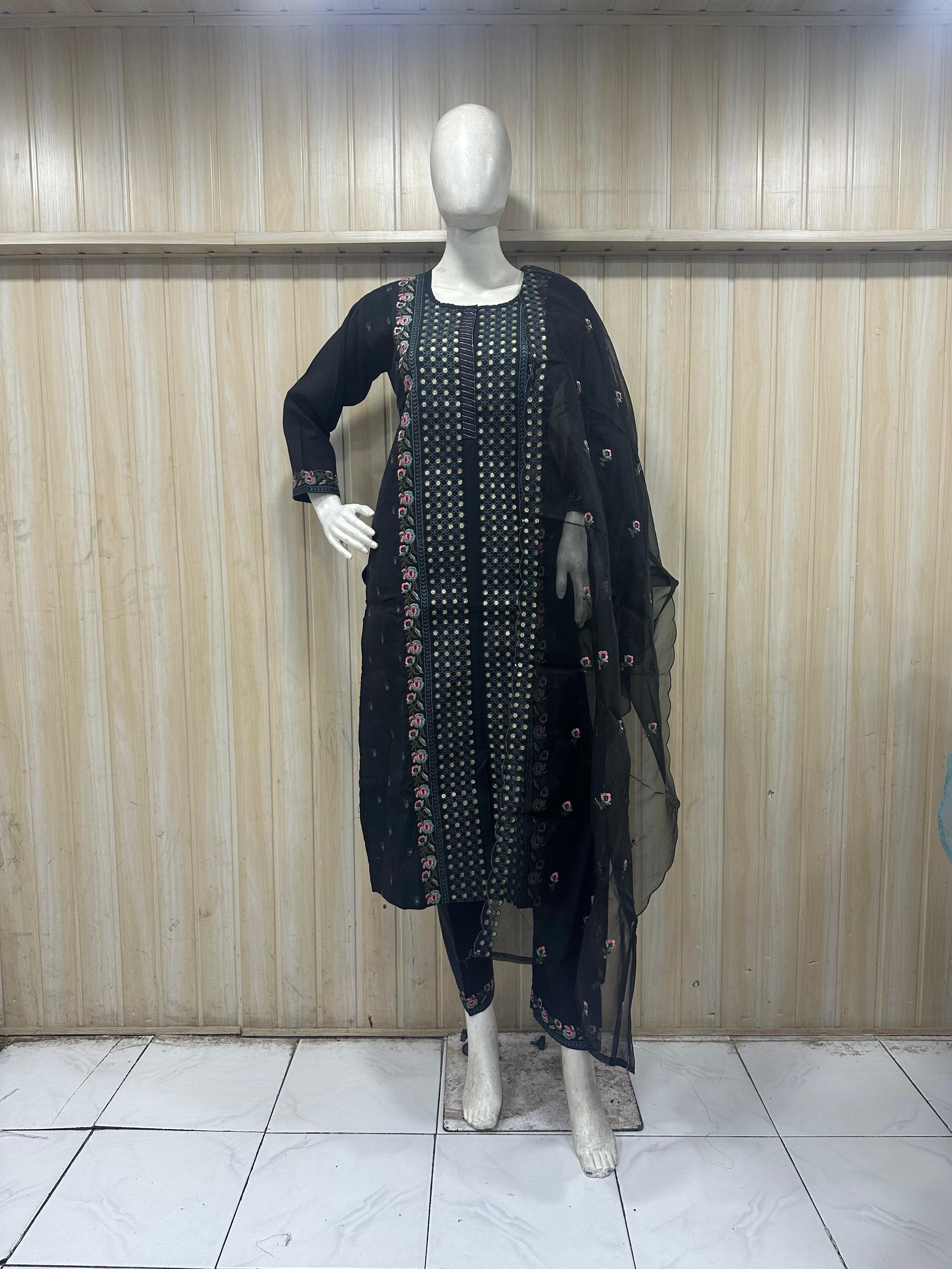 Black traditional outfit with sheer dupatta on a mannequin against a striped