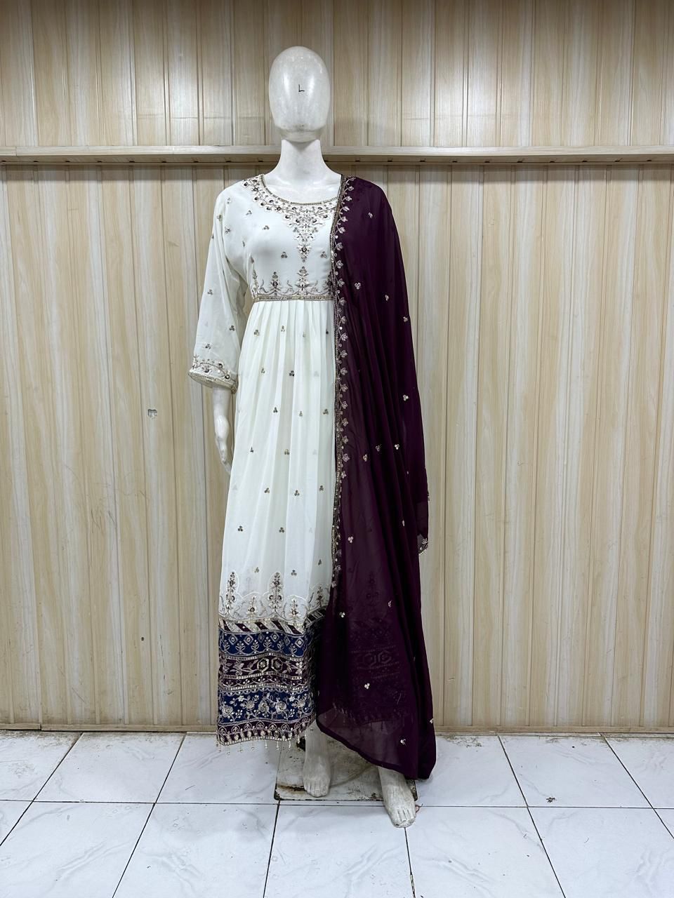 Mannequin wearing a white and purple traditional outfit with a plain background