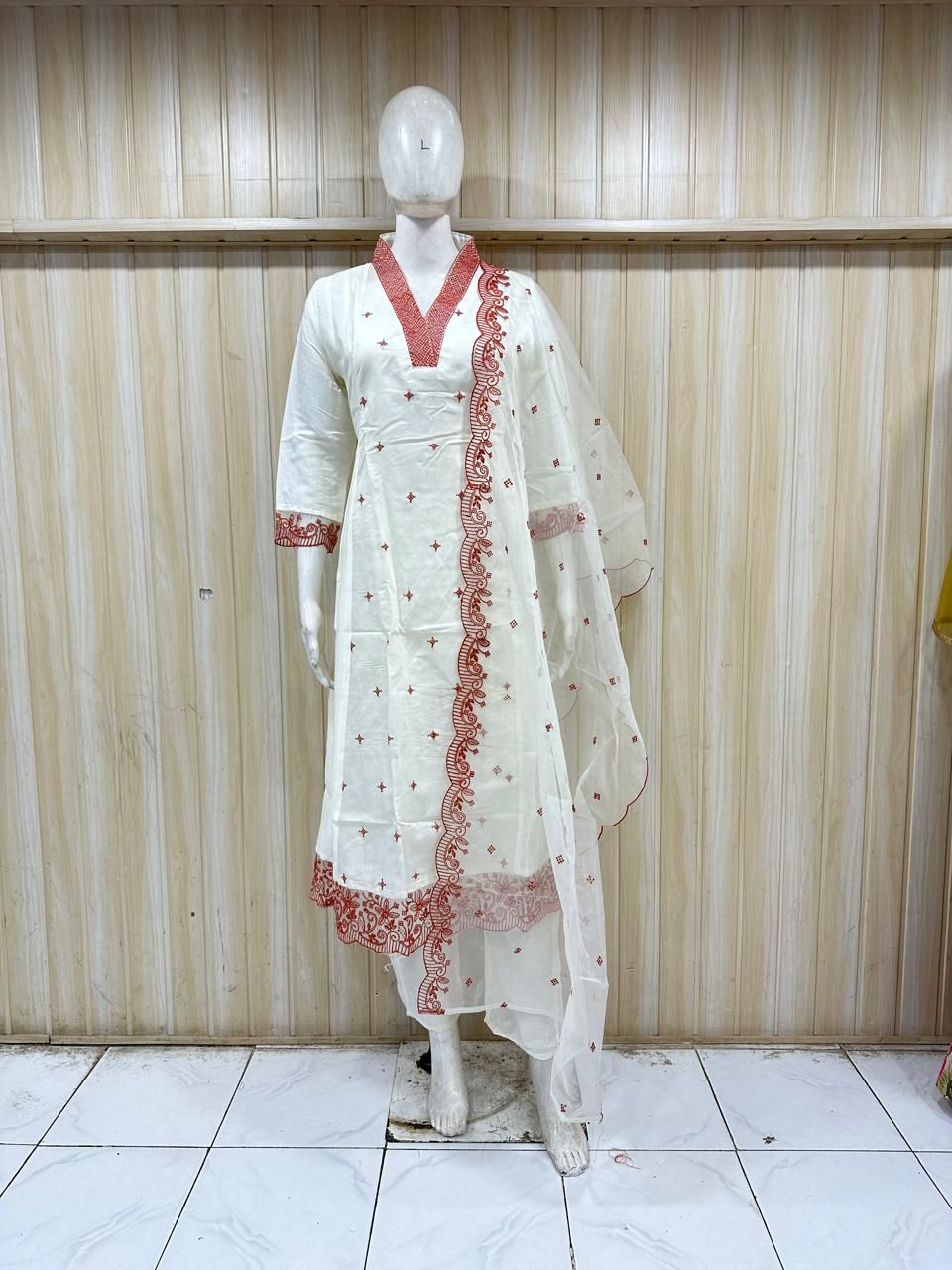 White embroidered traditional outfit on a mannequin against a striped
