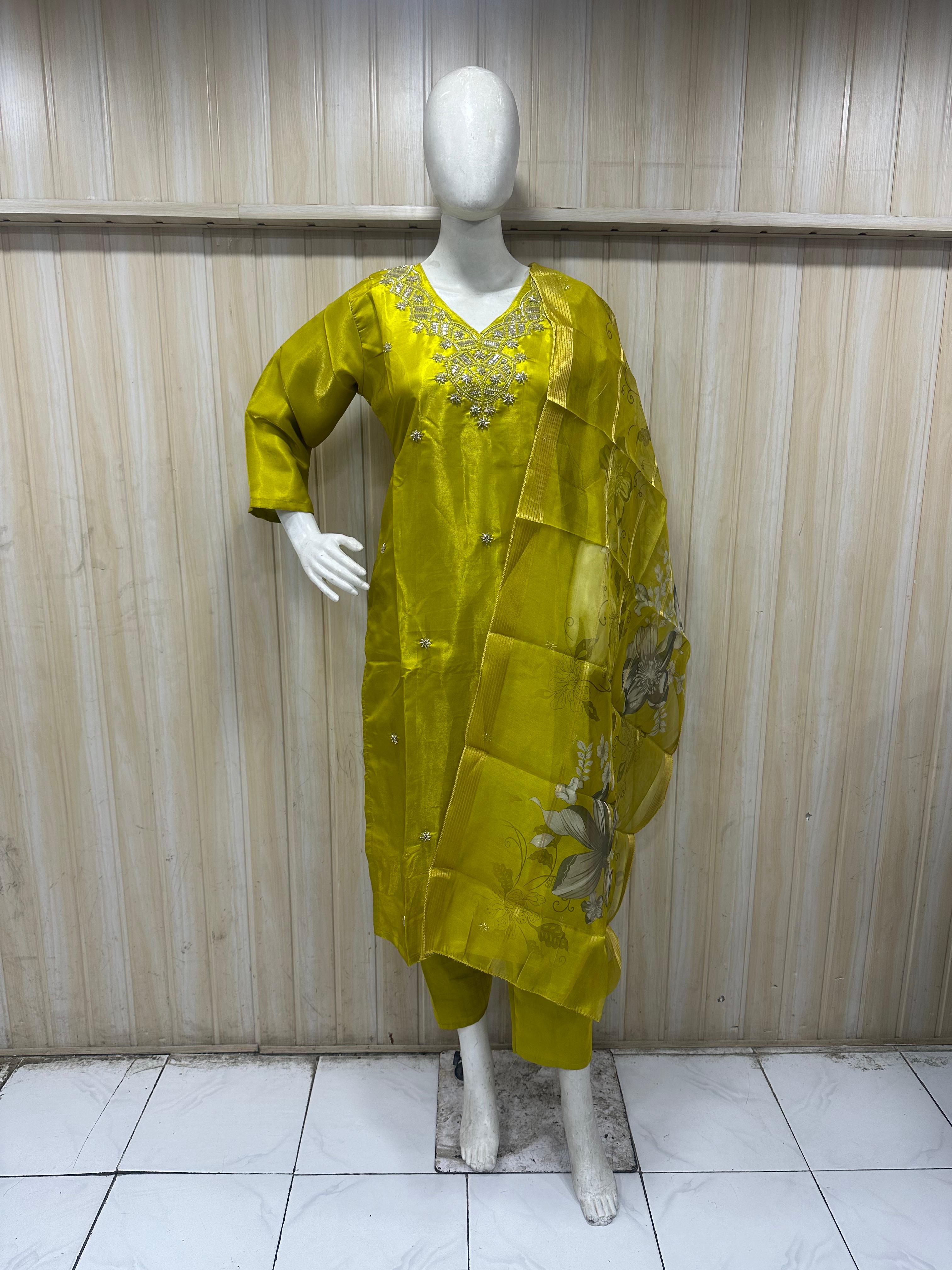Mannequin wearing a yellow embroidered outfit against a striped