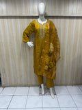 Mannequin wearing a mustard yellow outfit with floral embroidery against a striped