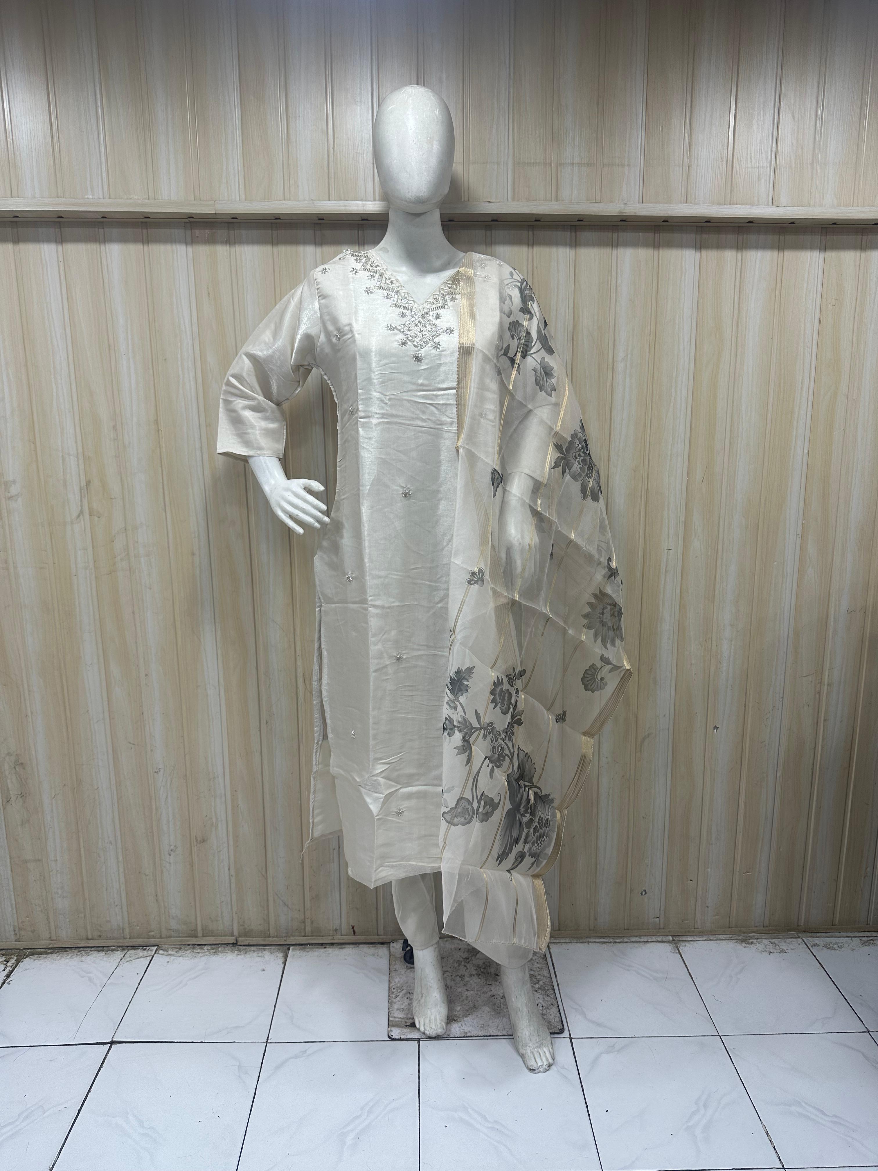 Mannequin wearing a white outfit with floral embroidery against a striped