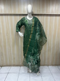 Green saree with a floral pattern on a mannequin against a wooden panel background