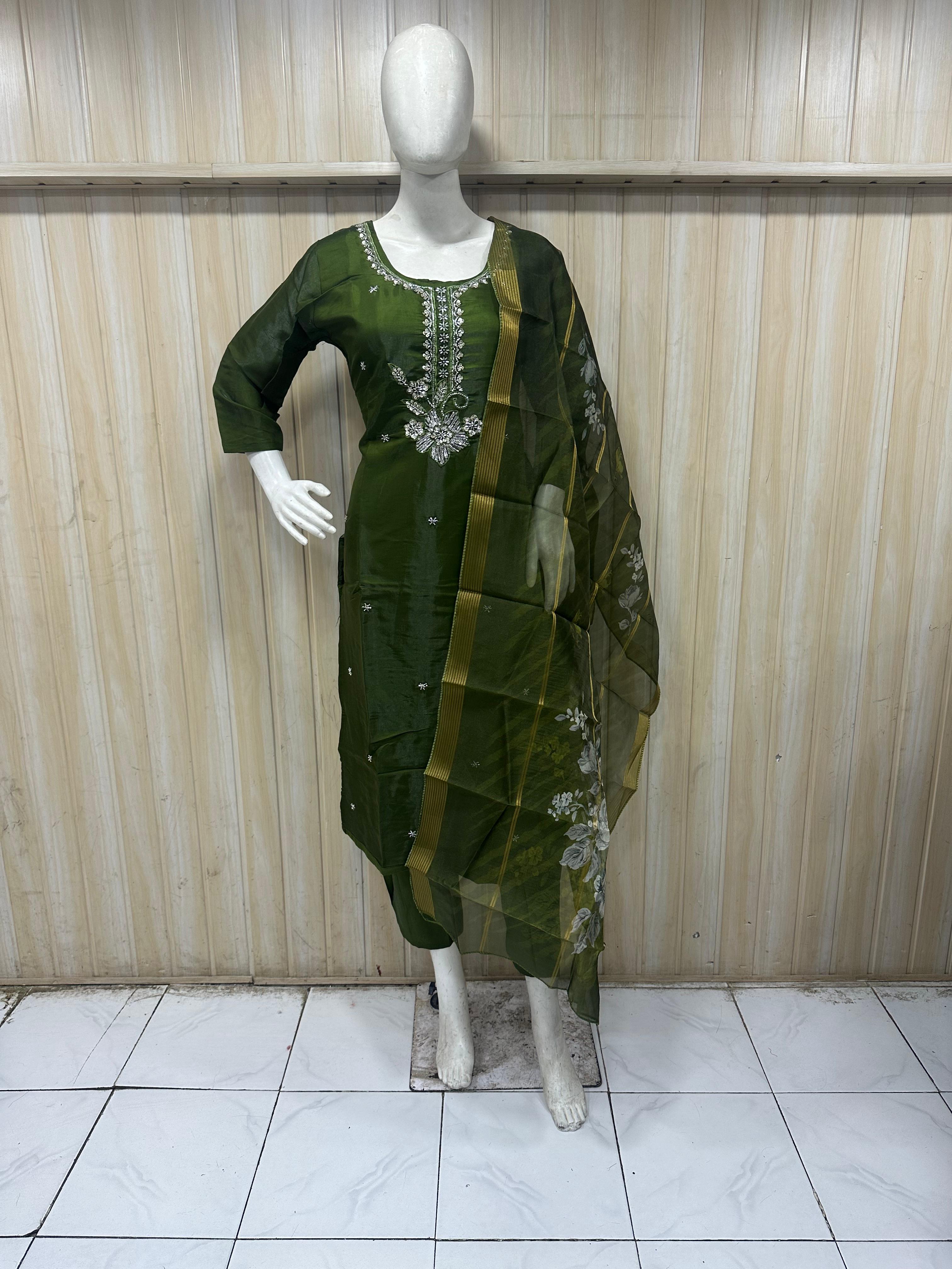 Green traditional outfit with white embroidery on a mannequin against a striped