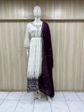 white traditional outfit with embroidery on a mannequin against a striped