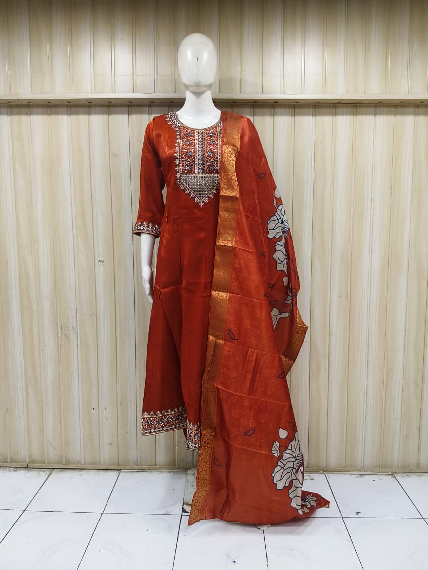 Orange traditional outfit with intricate patterns on a mannequin against a striped