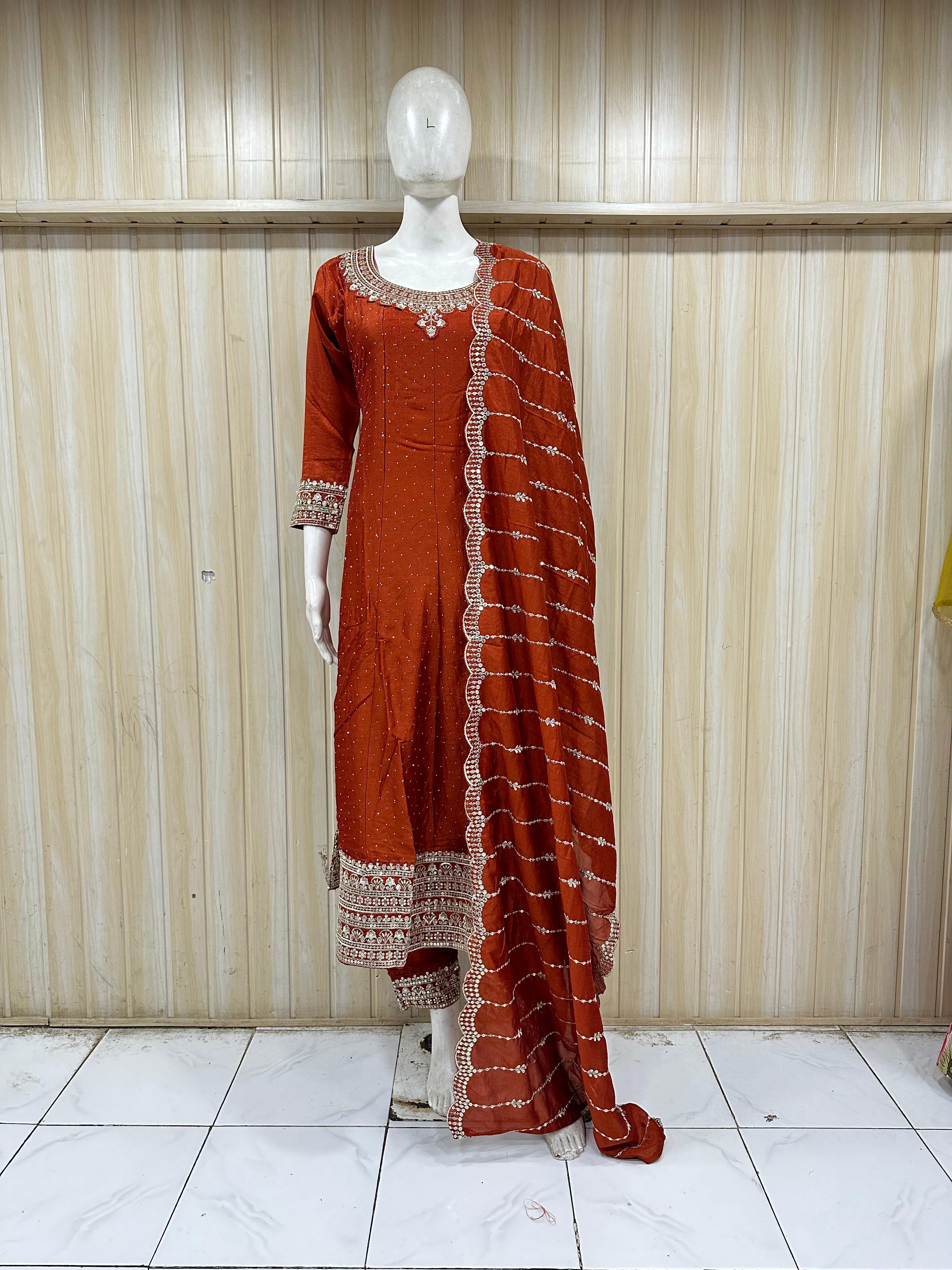 Mannequin wearing a rust-colored traditional outfit with intricate patterns against a striped