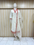 White traditional outfit with red embroidery on a mannequin against a striped