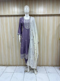 Mannequin wearing a purple and white embroidered outfit against a striped