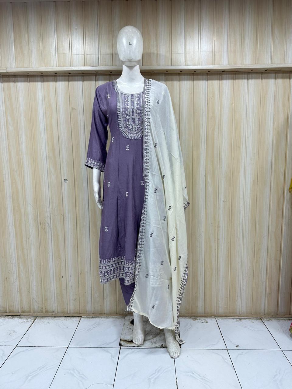 Mannequin wearing a purple and white embroidered outfit against a striped