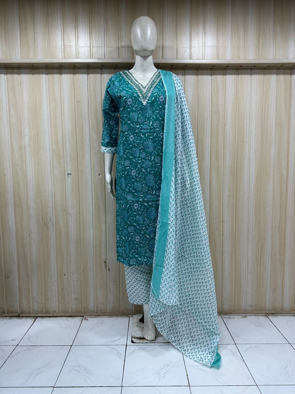 Teal traditional outfit with matching dupatta on a mannequin against a wooden panel background.