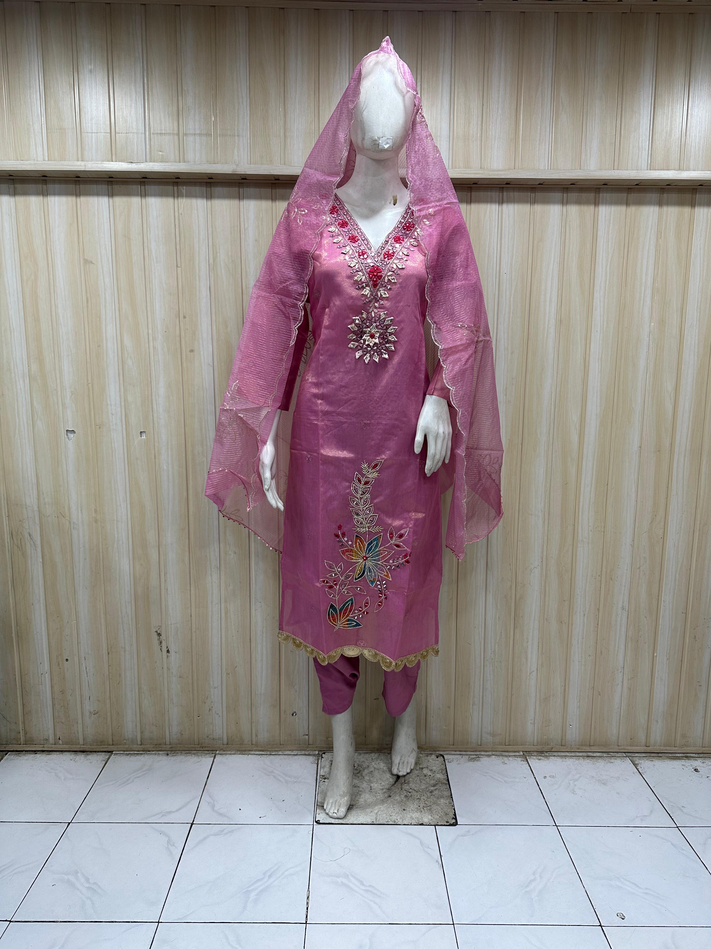 Mannequin wearing a pink floral dress with a dupatta against a wooden panel background.