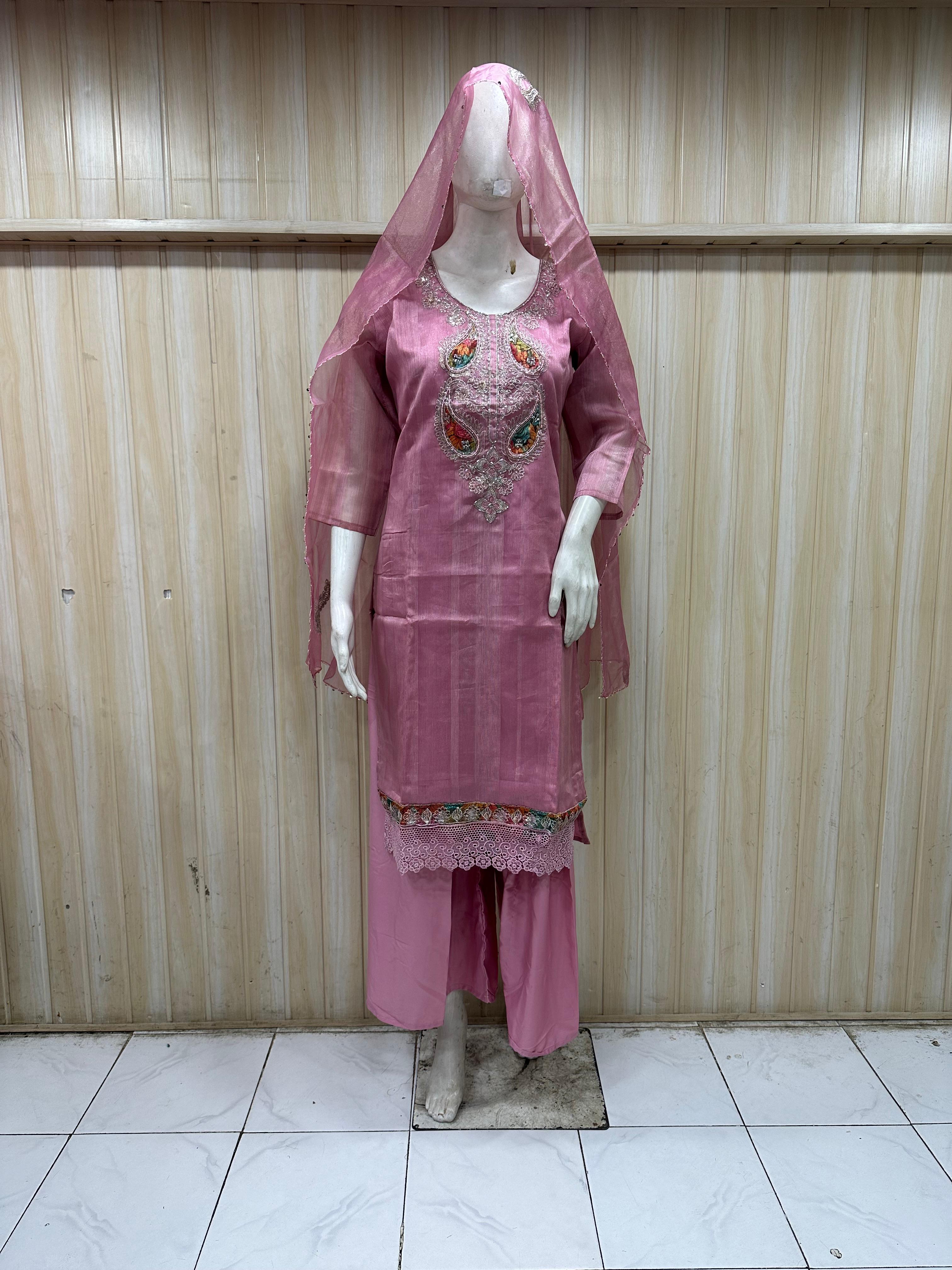 Mannequin wearing a pink traditional outfit with embroidery against a striped