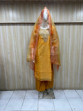 Yellow traditional outfit with an orange dupatta on a mannequin against a striped