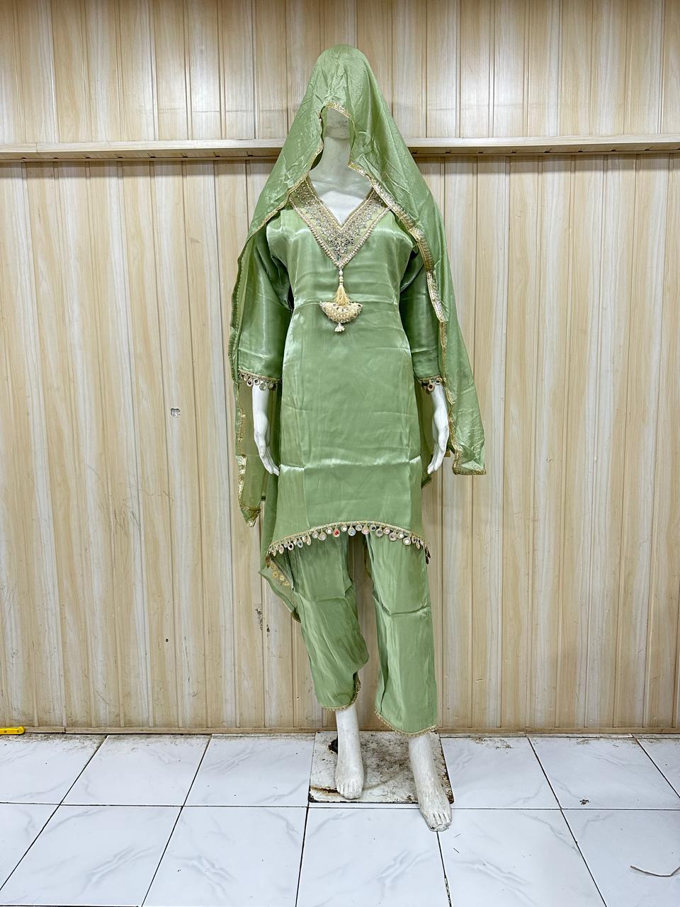 Green traditional outfit with a headscarf on a mannequin against a striped