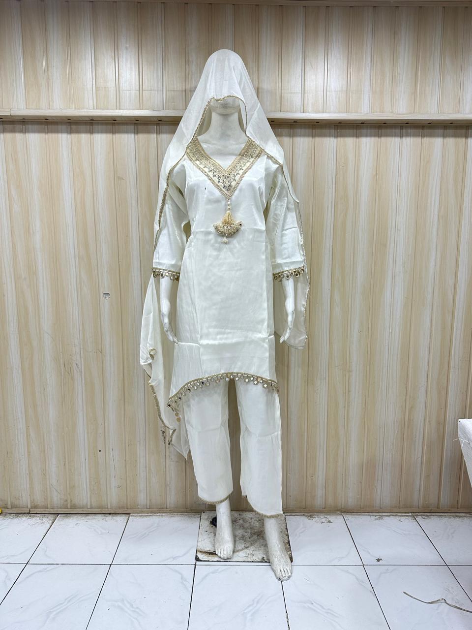 White traditional outfit with embroidered details on a mannequin against a striped