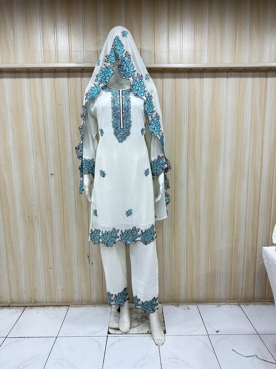 White and blue traditional outfit with embroidered details on a mannequin against a striped