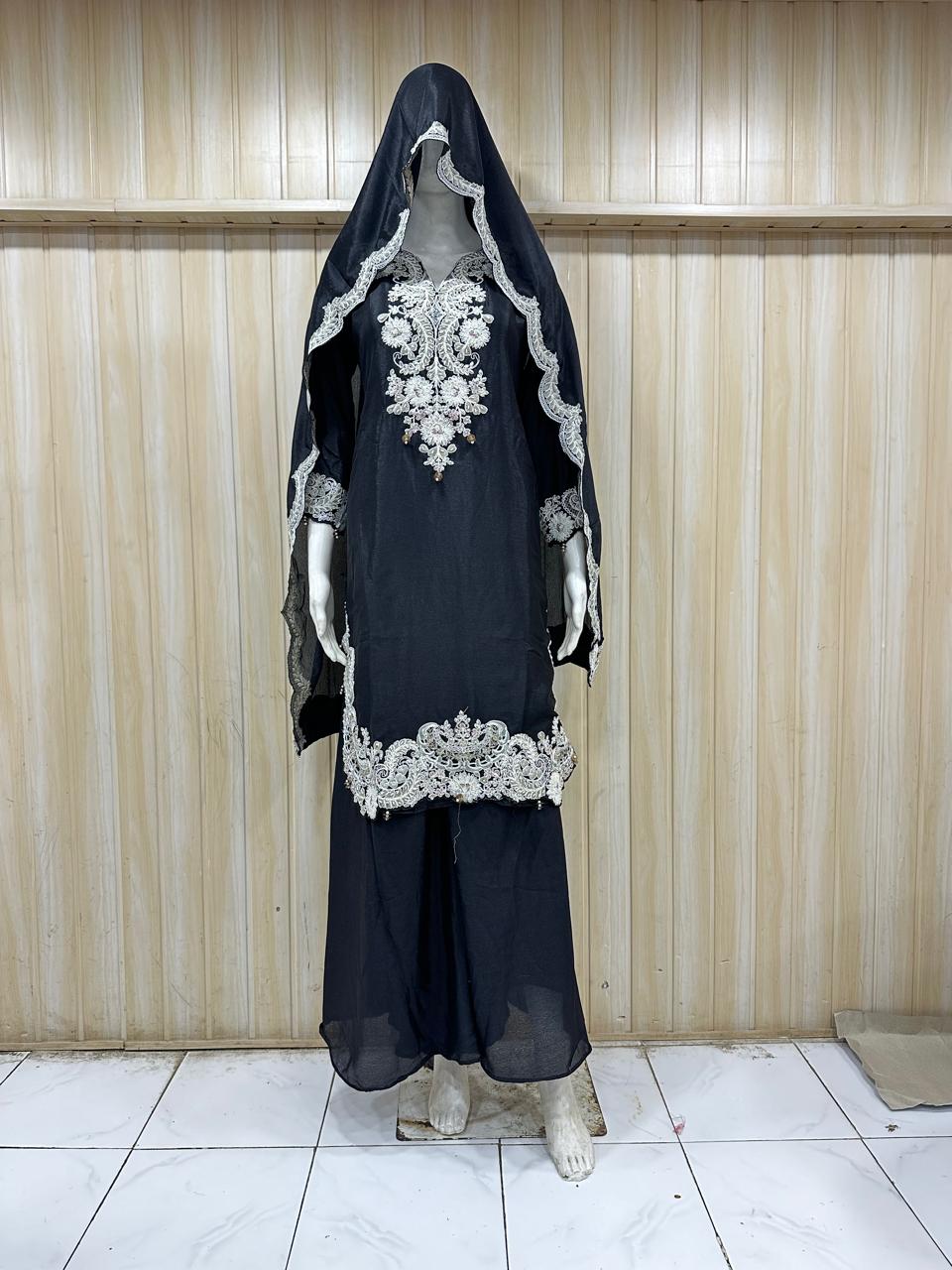 Black outfit with white embroidery on a mannequin against a striped