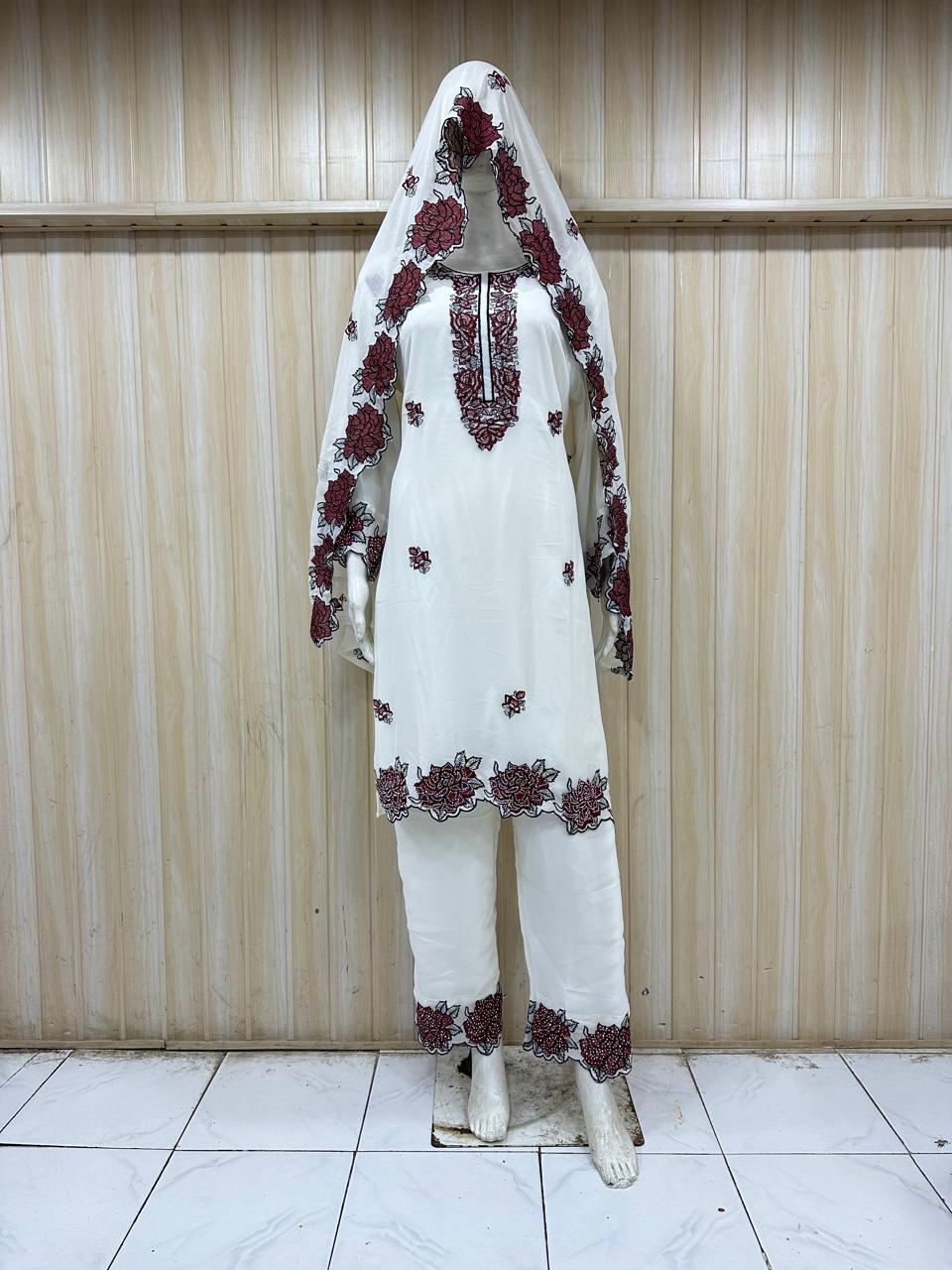 White embroidered outfit with maroon details on a mannequin against a striped