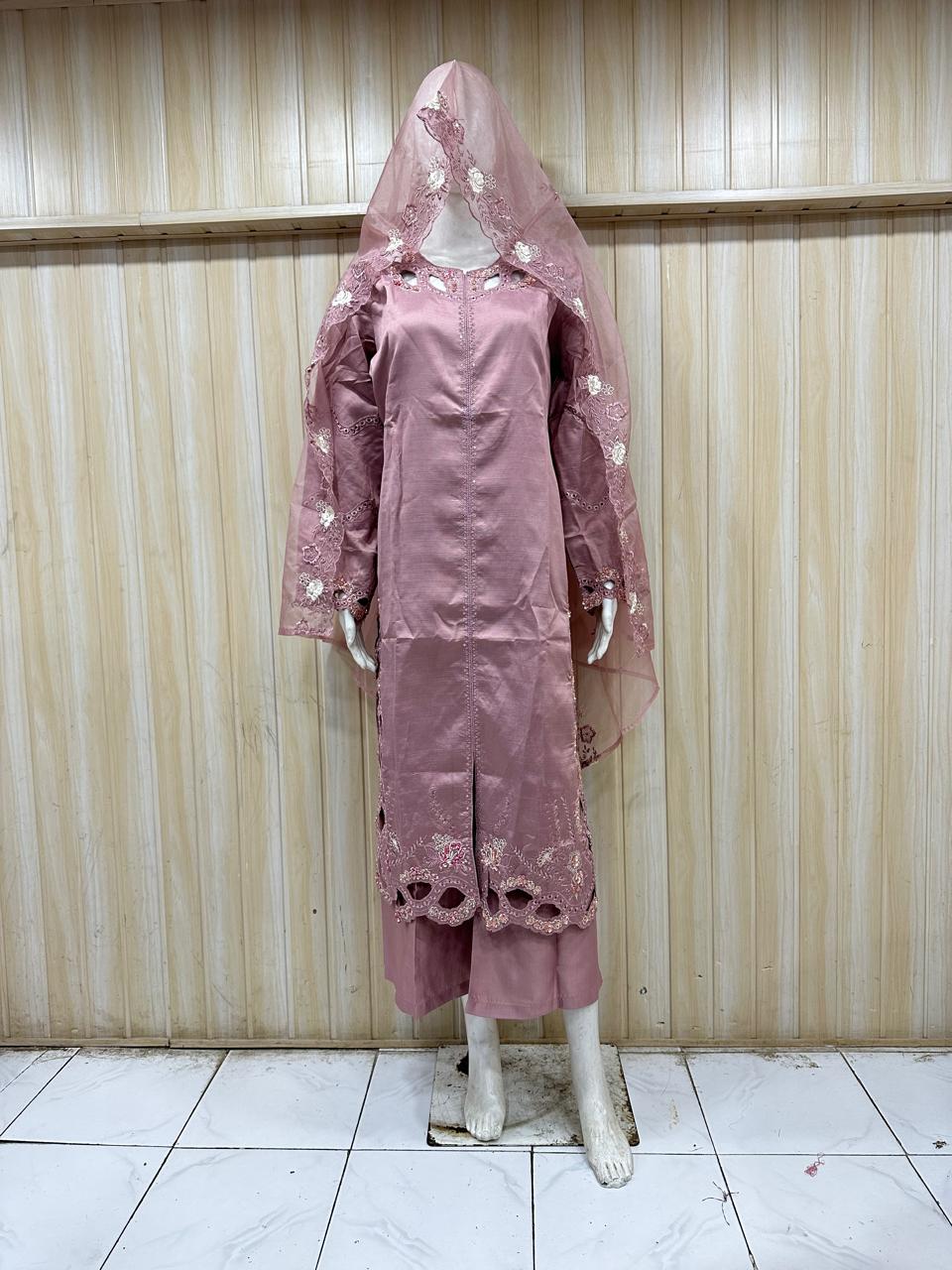 Mannequin wearing a pink traditional outfit with a matching headscarf against a striped