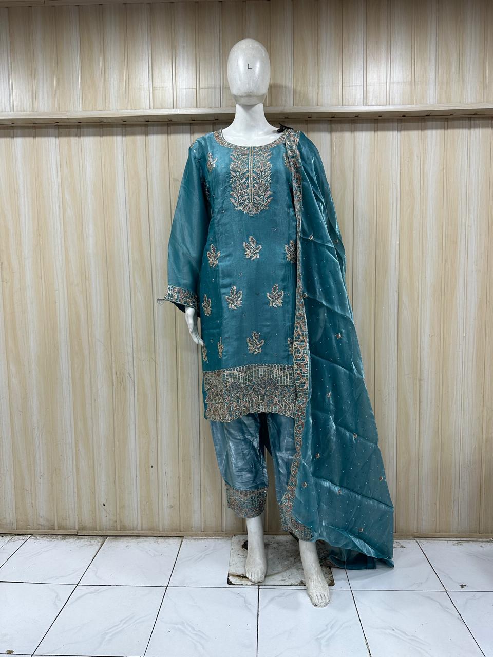 blue embroidered outfit with a floral dupatta on a mannequin against a striped