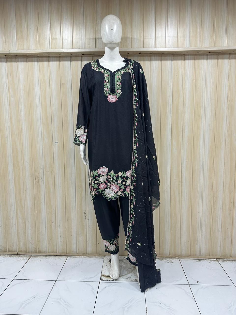 Black embroidered outfit with a dupatta on a mannequin against a striped