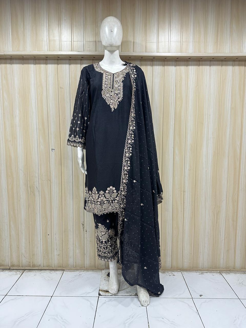 Black embroidered outfit on a mannequin against a striped