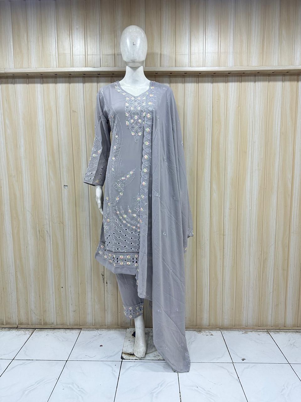 Mannequin wearing a gray embroidered outfit with a long dupatta against a wooden panel background.