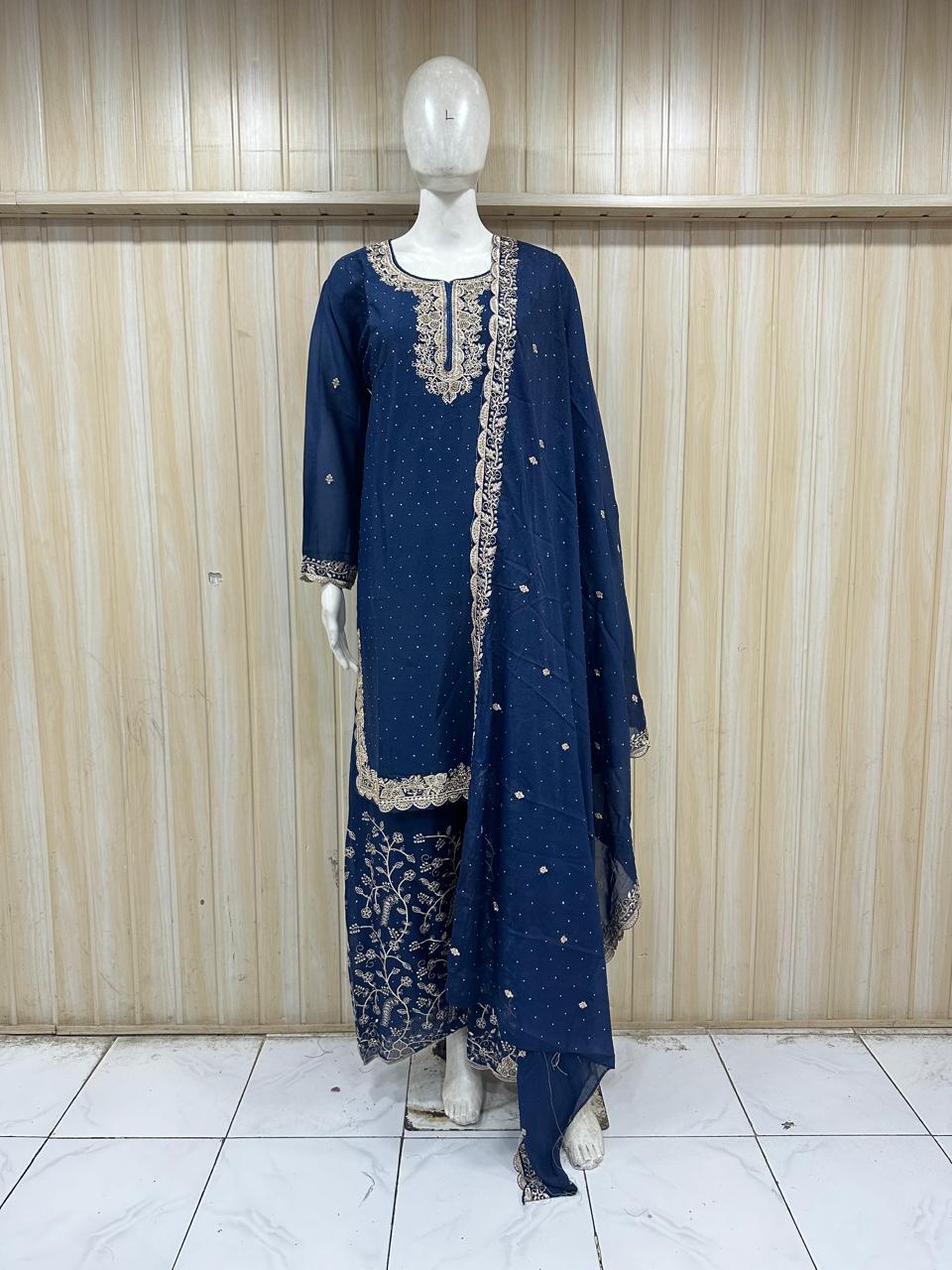 Navy blue embroidered outfit on a mannequin against a striped