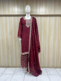 Maroon traditional outfit with intricate patterns on a mannequin against a striped