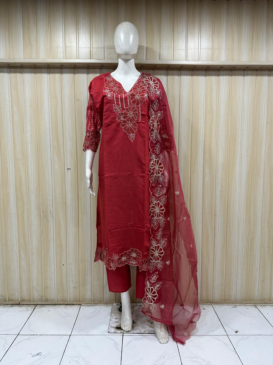 Red embroidered outfit with a dupatta on a mannequin against a striped
