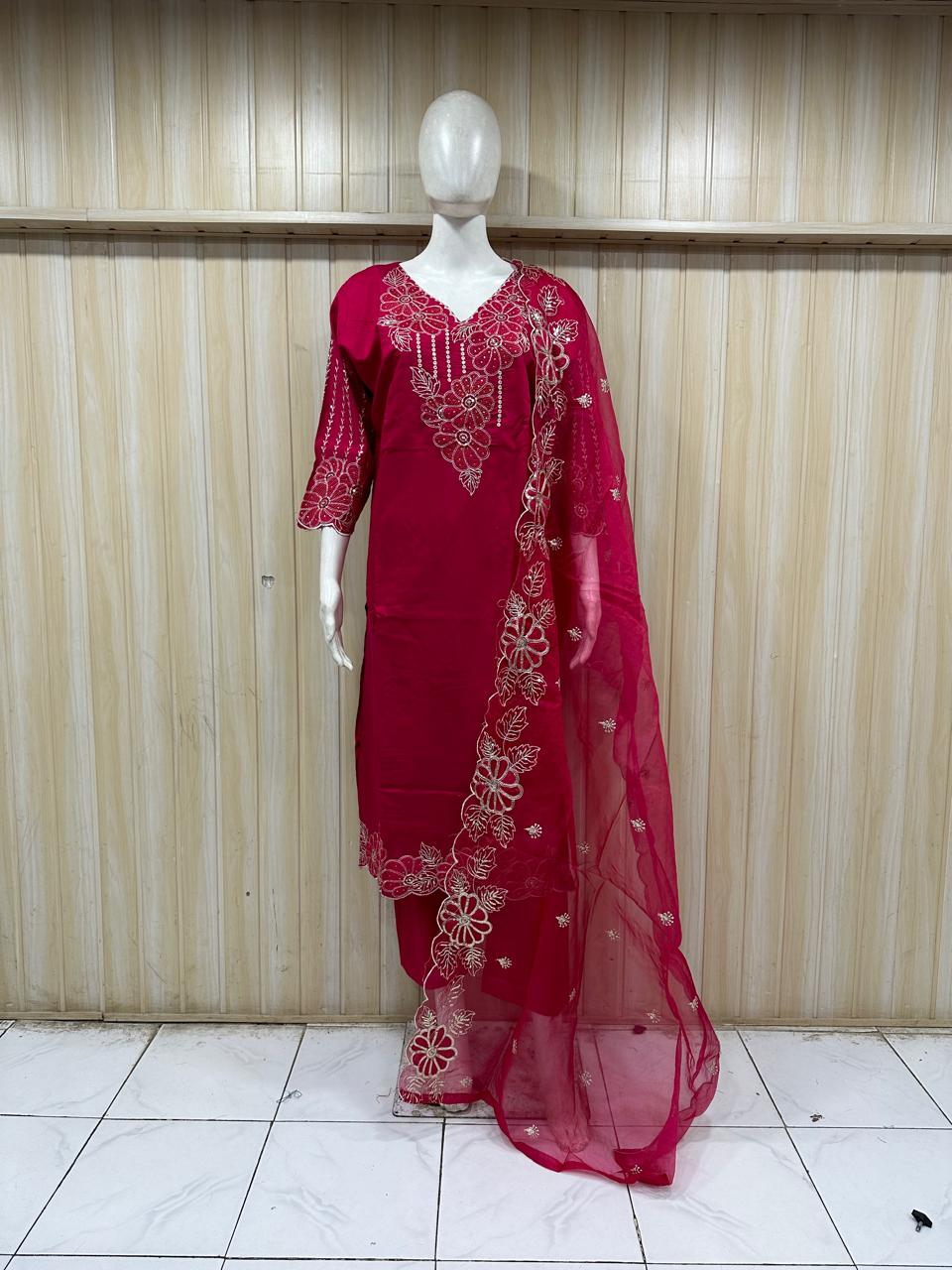 Red embroidered traditional outfit on a mannequin against a striped