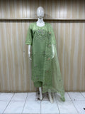 Green embroidered dress on a mannequin against a striped