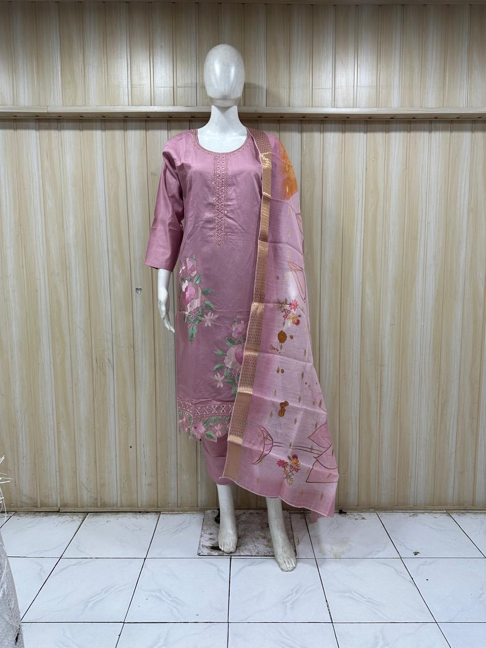 Mannequin wearing a pink colored embroidered outfit against a striped