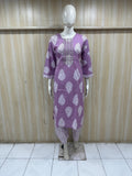 Purple dress with white patterns on a mannequin against a wooden panel background