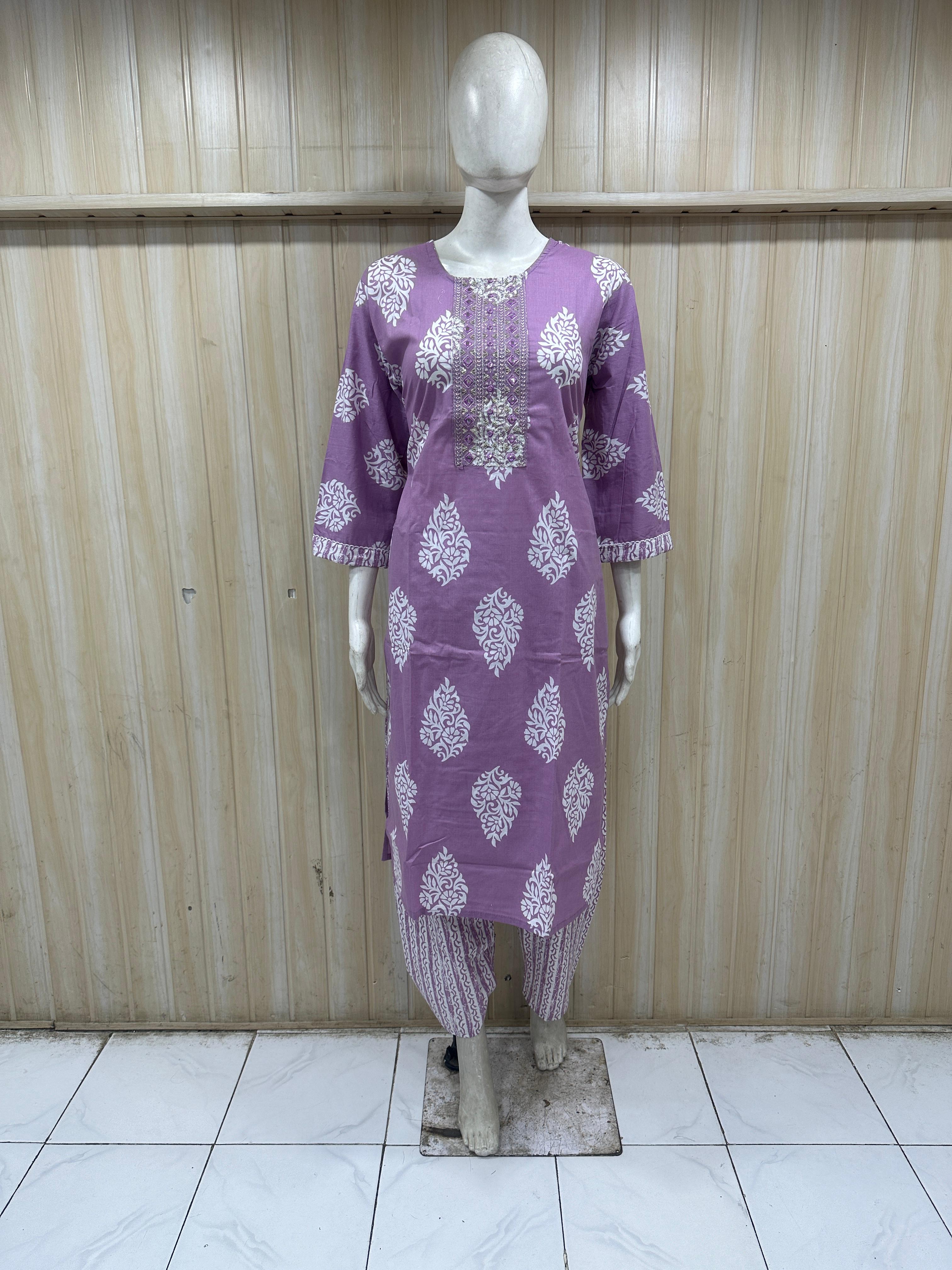 Purple dress with white patterns on a mannequin against a wooden panel background