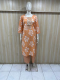 Orange dress with white floral pattern on a mannequin against a striped