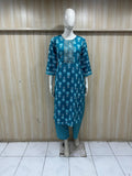 Mannequin wearing a blue dress with white patterns against a wooden panel background