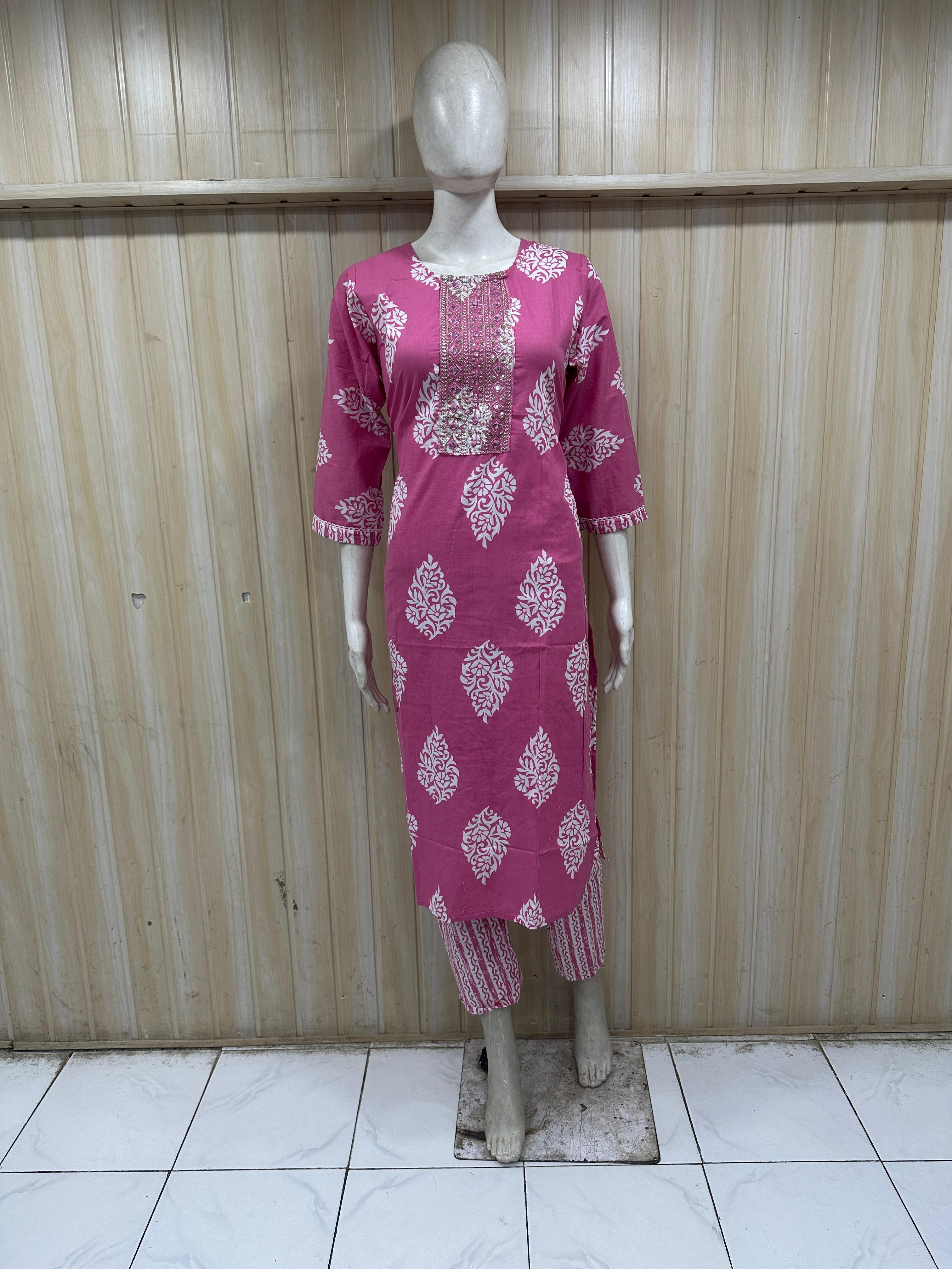Mannequin wearing a pink dress with white patterns against a striped