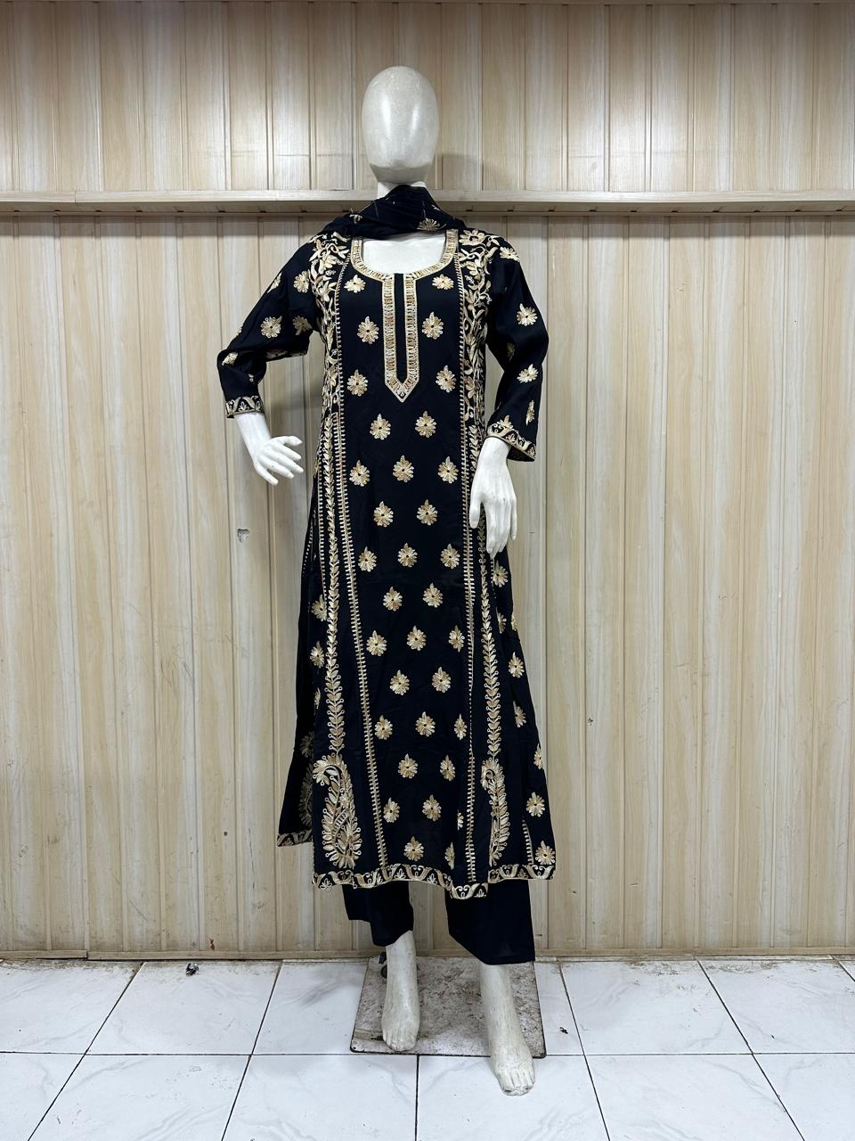 Black embroidered traditional outfit on a mannequin against a striped