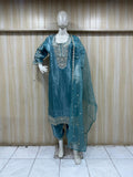 Teal embroidered outfit on a mannequin against a wooden panel background  ChatGPT2:09 PM