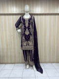 Mannequin wearing a dark purple embroidered outfit against a wooden panel background