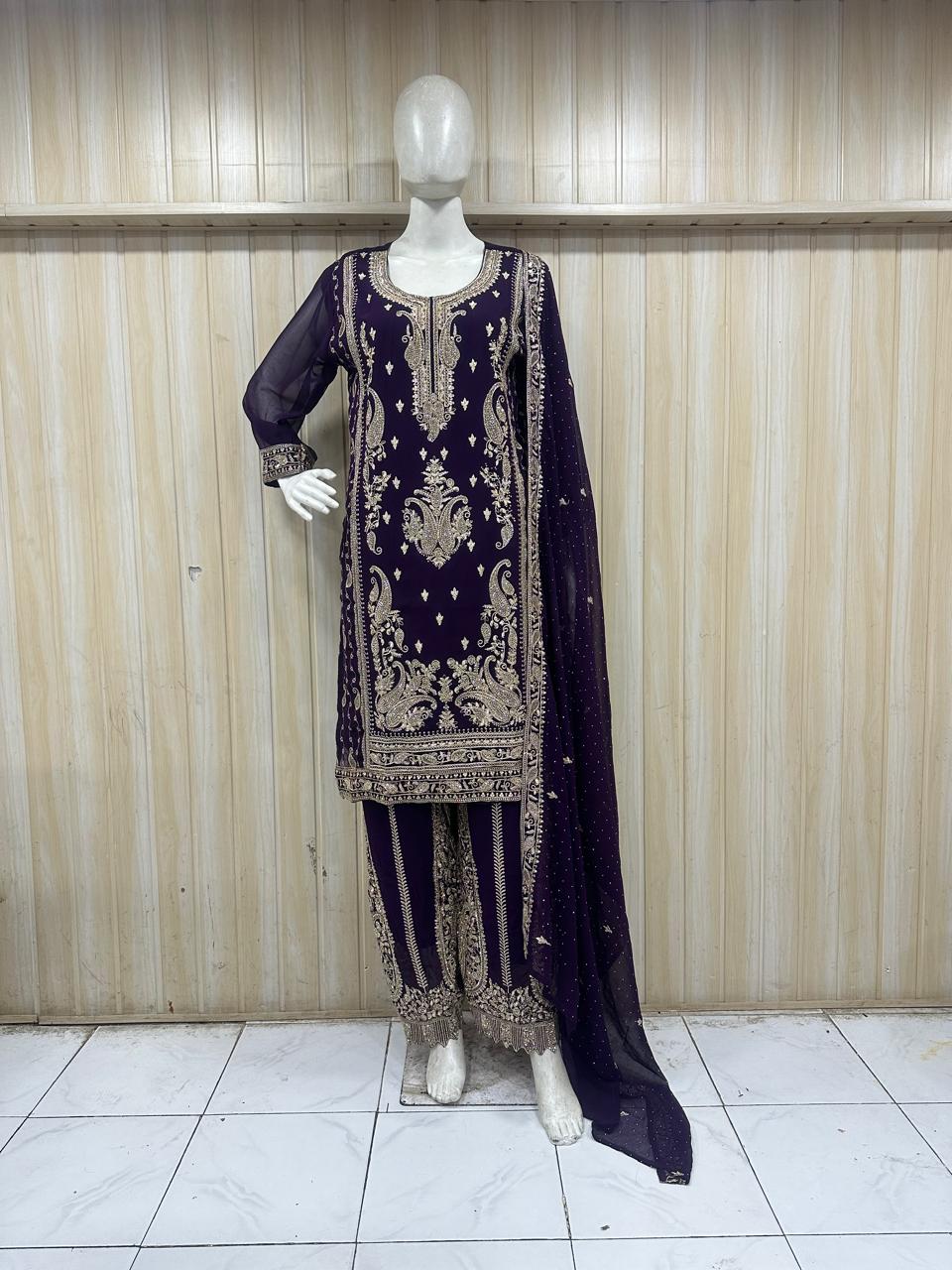 Mannequin wearing a dark purple embroidered outfit against a wooden panel background