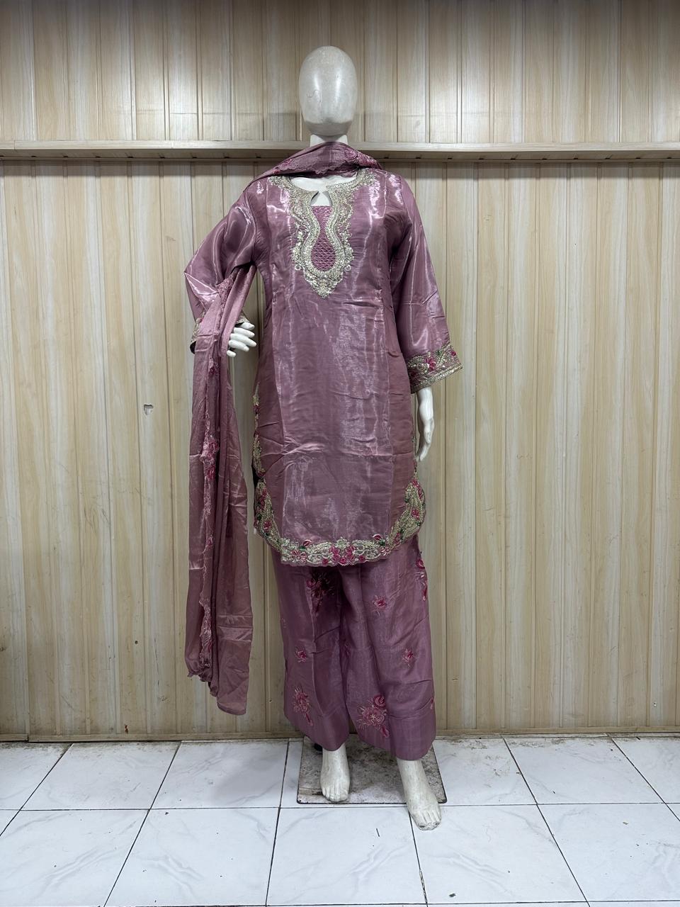 Mannequin wearing a mauve traditional outfit with intricate patterns against a striped