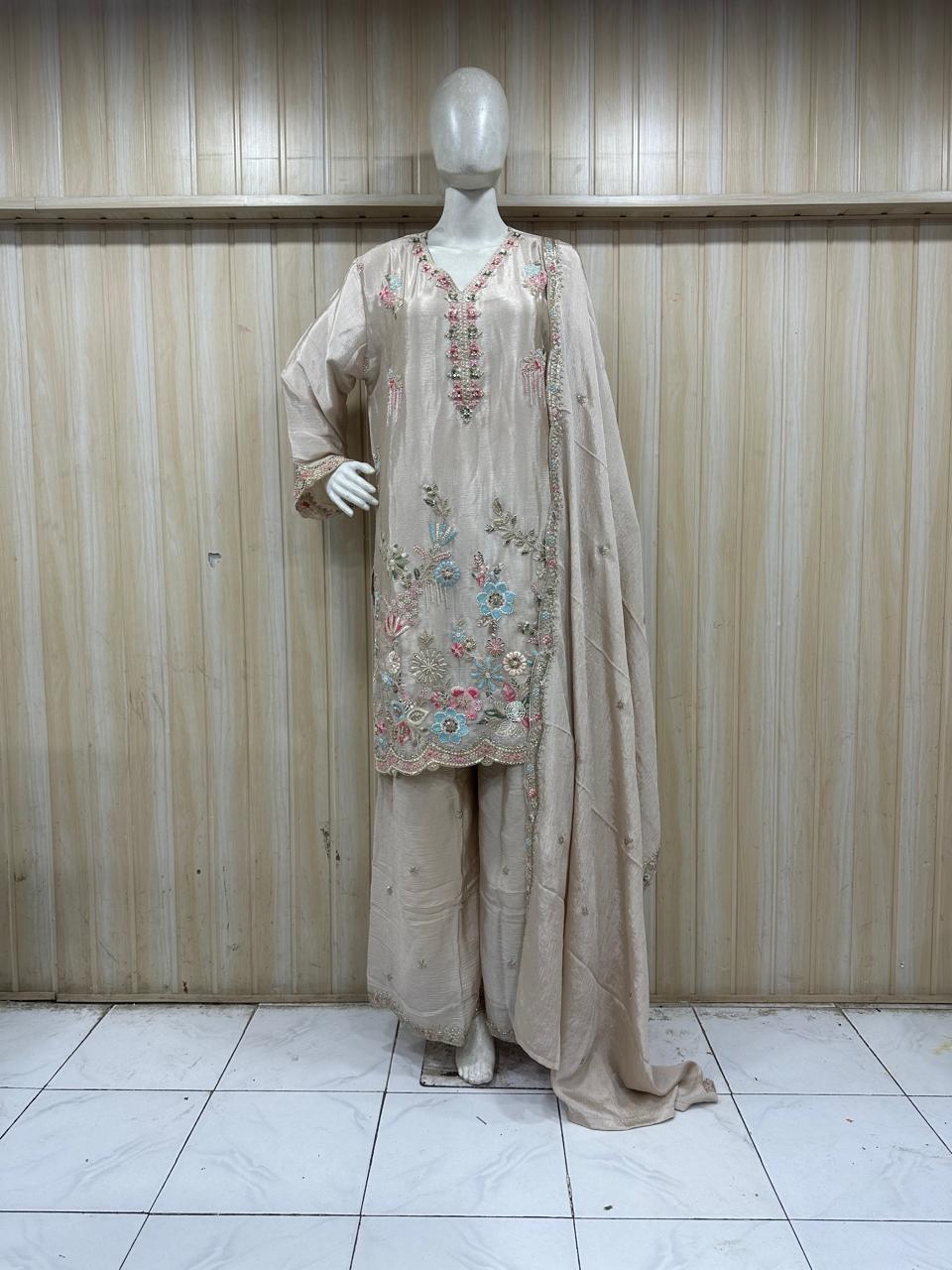 Mannequin wearing a beige embroidered outfit against a striped