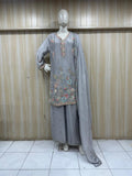 Mannequin wearing a gray embroidered outfit against a wooden paneled